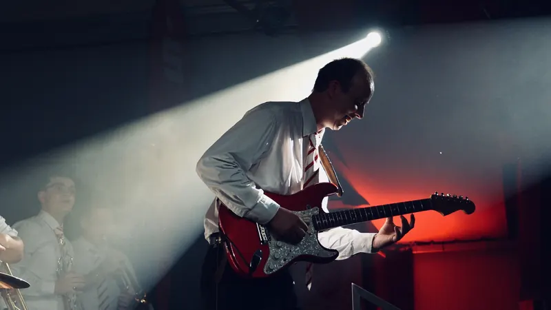 Gitarrist mit roter E-Gitarre im Lichtkegel