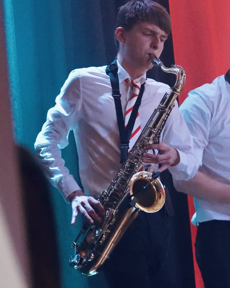 Saxophonist vor rotem Bühnenbanner